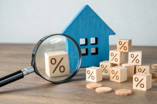 © Foto Fusion - stock.adobe.com Foto: Lupe, Holzhaus und Würfel mit Prozentzeichen