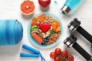 © New Africa - stock.adobe.com Foto: Bowl mit Obst darum angeordnet liegen Fitnessgeräte