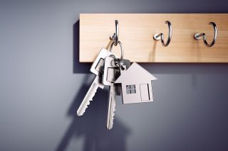 © peterschreiber.media - stock.adobe.com Foto: Schlüsselbund mit Schlüsselanhänger in Hausform auf Schlüsselwand